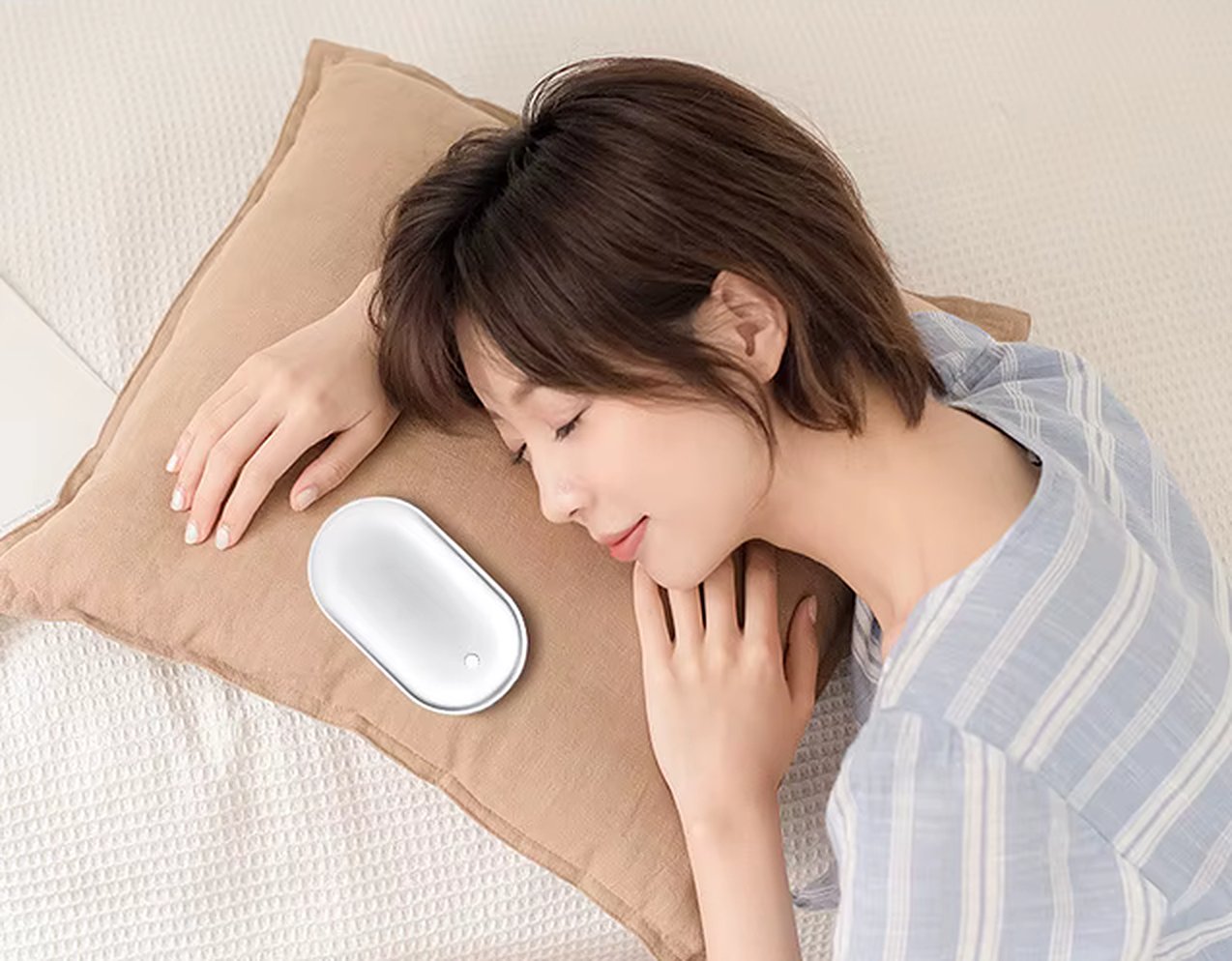 Une femme allongée sur un coussin, un galet chauffant SALO posé près d'elle